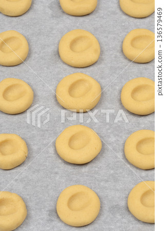 Raw thumbprint cookie dough on parchment paper Raw thumbprint cookie dough on parchment paper 136579469