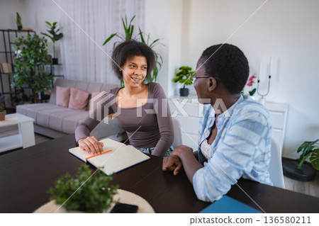 Mother and daughter studying together at home Mother and daughter studying together at home 136580211