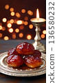 Traditional Indian gulab jamun served on an ornate silver plate with syrup, festive candle and warm bokeh lights in background, perfect for Diwali celebration 136580232