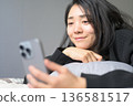 A Japanese woman operating a smartphone in bed 136581517