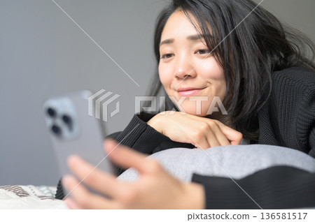 A Japanese woman operating a smartphone in bed 136581517
