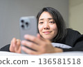 A Japanese woman operating a smartphone in bed 136581518
