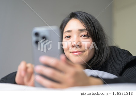 一名日本女性在床上操作智慧型手機 136581518