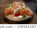 Grilled salmon sashimi on plate, served in a restaurant, with salt lemon and wasabi 136582283