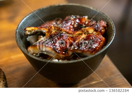 Unagi don. Grilled eel with sweet sauce rice bowl on wooden table. Unagi don. Grilled eel with sweet sauce rice bowl on wooden table. 136582284