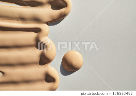 Beige liquid foundation smears and drop on light grey background Beige liquid foundation smears and drop on light grey background 136583492