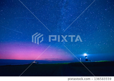 A low-latitude aurora, lighthouse lights, and meteor showers appear in the Hokkaido night sky 136583559