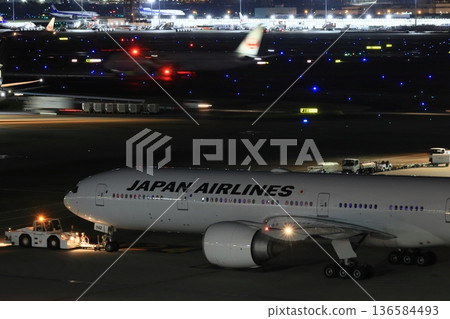 A passenger plane being towed away for a night flight A passenger plane being towed away for a night flight 136584493