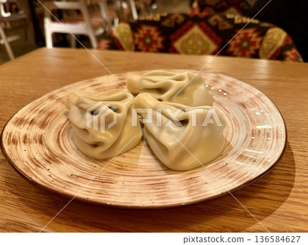 Handmade Dumplings On Wooden Table, Five Pleated Khinkali Arranged On Ceramic Plate, Warm Natural Light, Textured Tabletop Grain Visible, CloseUp Culinary Still Life Conveying Rustic 136584627