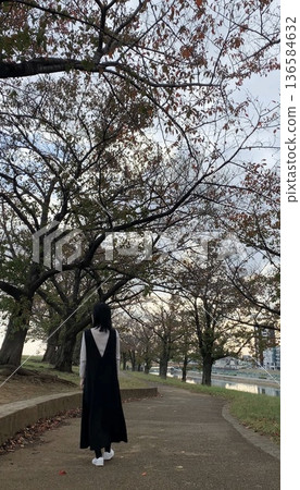 Woman walking in autumn park 136584632