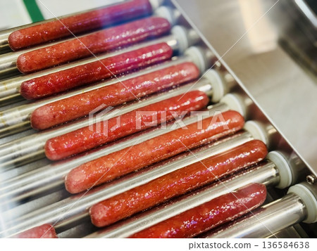 Long delicious hot dogs are sizzling on a roller grill in supermarket indoor, making them the perfect choice for outdoor gatherings and events. Close-up 136584638