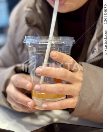 Hands Holding Iced Coffee Cup CloseUp, Student Gripping Cold Beverage With Both Hands At Cafe Table, Straw Near Lips, Condensation Beading On Plastic Cup, Casual Winter Jacket, Smartphone Hands Holding Iced Coffee Cup CloseUp, Student Gripping Cold Beverage With Both Hands At Cafe Table, Straw Near Lips, Condensation Beading On Plastic Cup, Casual Winter Jacket, Smartphone 136584679