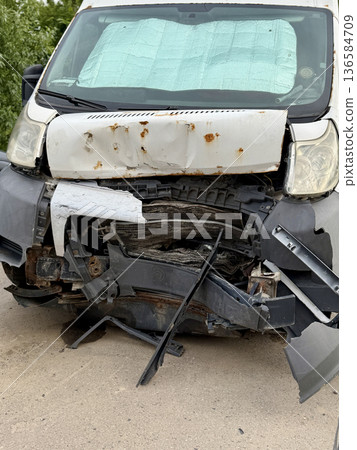 This minibus was significantly damaged as a result of a serious head-on collision. A seriously damaged grey minibus, which shows significant collision marks in the front and extensive rust marks. This minibus was significantly damaged as a result of a serious head-on collision. A seriously damaged grey minibus, which shows significant collision marks in the front and extensive rust marks. 136584709