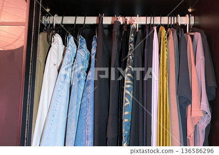 A close-up view of various clothes hanging in a closet 136586296