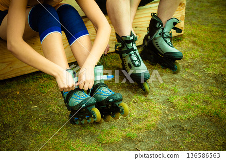 Woman and man putting on roller skates Woman and man putting on roller skates 136586563