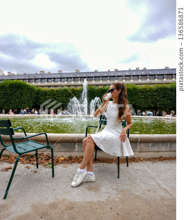 Woman in white dress relaxing by fountain in Paris 136586871