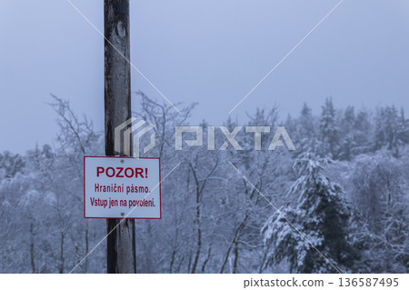 Warning sign marking border zone in winter forest Warning sign marking border zone in winter forest 136587495
