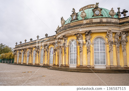 Sanssouci Palace of King Frederick II in Potsdam, Germany. Old building architecture in Rococo style. Yellow facade wall and windows. Sanssouci Palace of King Frederick II in Potsdam, Germany. Old building architecture in Rococo style. Yellow facade wall and windows. 136587515