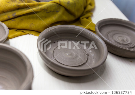 Raw clay bowls drying on a workbench in a pottery studio 136587784
