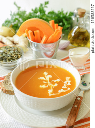 Autumn season cream soup. Pumpkin soup puree from the ingredients of a pumpkin carrot potato ginger onion garlic spices. Close-up. Autumn season cream soup. Pumpkin soup puree from the ingredients of a pumpkin carrot potato ginger onion garlic spices. Close-up. 136588237