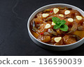 Korean style soy marinated shrimp served with garlic slices, chili, and fresh herbs in a white bowl on dark background. Popular Korean seafood dish known as saeu jang, premium raw shrimp, 136590039