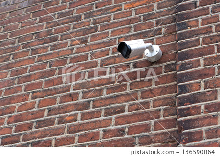 Surveillance camera on old brick wall 136590064