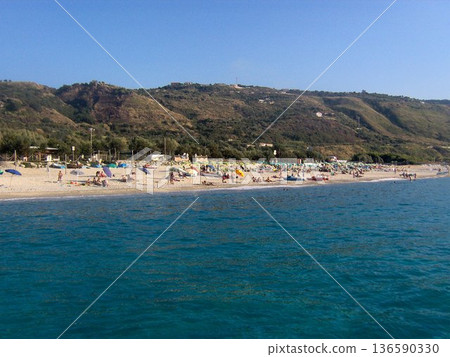 Beautiful panoramic view of the Calabrian coast during the summer season, featuring turquoise crystal-clear waters, dramatic rocky cliffs, and charming seaside scenery under bright blue skies. The 136590330