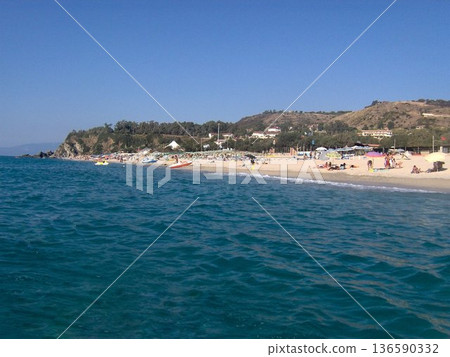 Beautiful panoramic view of the Calabrian coast during the summer season, featuring turquoise crystal-clear waters, dramatic rocky cliffs, and charming seaside scenery under bright blue skies. The 136590332