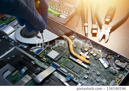 Side view of a technician repairing a laptop. Side view of a technician repairing a laptop. 136590596