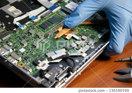 The technician is repairing the laptop. The technician is repairing the laptop. 136590599