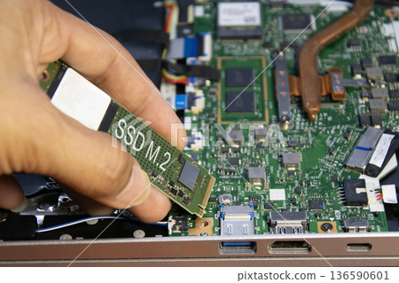 The technician is installing an M.2 hard drive. The technician is installing an M.2 hard drive. 136590601