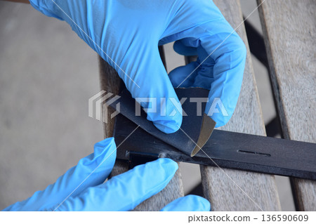 The mechanic is using sandpaper to sand the workpiece. The mechanic is using sandpaper to sand the workpiece. 136590609