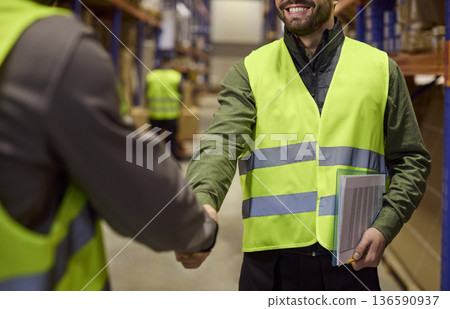 Smiling warehouse supervisor and worker handshake, logistics deal with checklist 136590937
