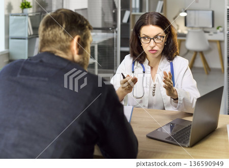 Doctor consulting patient in clinic, discussing diagnosis and treatment options 136590949
