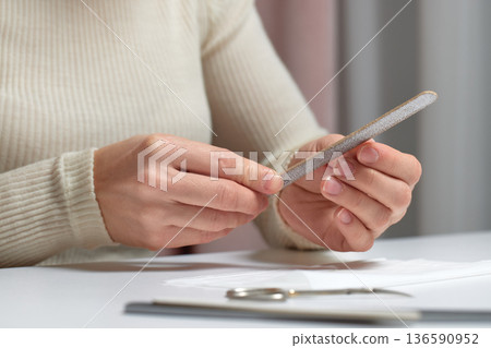 Woman performing manicure, filing her fingernails for personal care and beauty treatment Woman performing manicure, filing her fingernails for personal care and beauty treatment 136590952