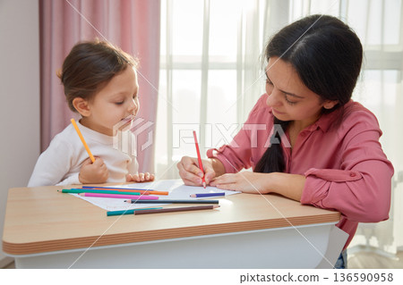 Mother and daughter drawing with colored pencils, engaging in creative home learning 136590958