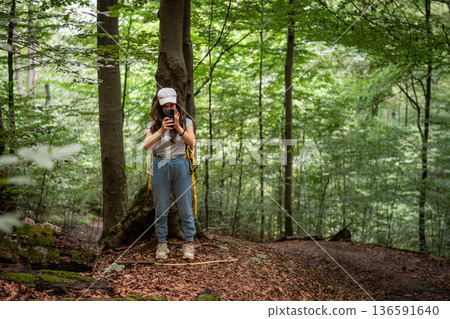 Young Woman Hiking in Green Forest with Walking Stick 136591640