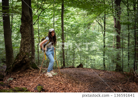Young Woman Hiking in Green Forest with Walking Stick 136591641