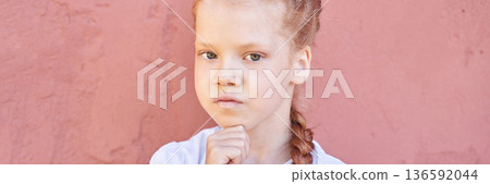 Thoughtful caucasian female child with red hair against pink wall in white Thoughtful caucasian female child with red hair against pink wall in white 136592044