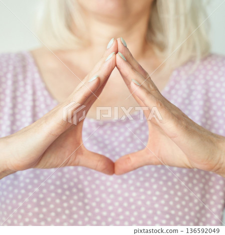 Caucasian mature female meditative hand gesture in calm environment, focus 136592049