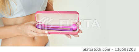 Female adult holding pink fitness kit with weights inside a case against light Female adult holding pink fitness kit with weights inside a case against light 136592208