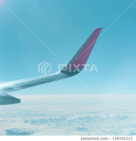 Airplane wing against clear blue sky above clouds in captivating view Airplane wing against clear blue sky above clouds in captivating view 136592221