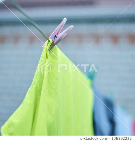 Bright green shirt hanging on clothesline with pink clothespin in outdoor Bright green shirt hanging on clothesline with pink clothespin in outdoor 136592222