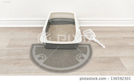 Odor-free litter box with gray mat and scoop positioned on wooden floor in a clean indoor space 136592301