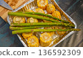 Fresh corn on the cob and asparagus arranged in a metal tray on a wooden surface with a knife in the background 136592309