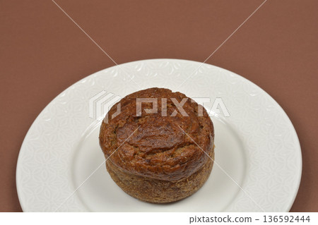 Small banana bread loaf on a white plate over a brown background 136592444