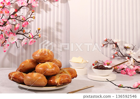 Festive Easter food concept. Easter buns are topped with a cross, jam, butter, and cherry blossom branches. English buns are baked on Good Friday and served with tea the morning before Easter Sunday 136592546