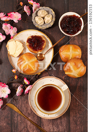 Happy Easter concept . Easter buns with a cross and jam, butter, and cherry blossoms. English buns are baked on Friday and served with tea the morning before Easter Sunday. A festive Easter treat. 136592553