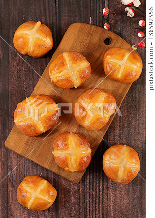 Festive Easter food concept.Easter hot cross buns on the kitchen table with eggs and cherry blossom branches. English buns are baked on Friday and served with tea the morning before Easter Sunday 136592556