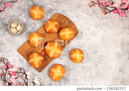 Happy Easter concept. Easter buns with a cross on a concrete table and cherry blossoms. English buns are baked on Friday and served with tea the morning before Easter Sunday. A festive Easter treat Happy Easter concept. Easter buns with a cross on a concrete table and cherry blossoms. English buns are baked on Friday and served with tea the morning before Easter Sunday. A festive Easter treat 136592557